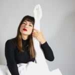 A woman sitting on a bed with a white sheet covering her face